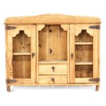 A pine hanging wall cabinet, with a moulded top above a recess, over two drawers flanked by two open