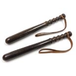 A near pair of turned hardwood truncheons, each mounted with a leather strap, 37cm long.