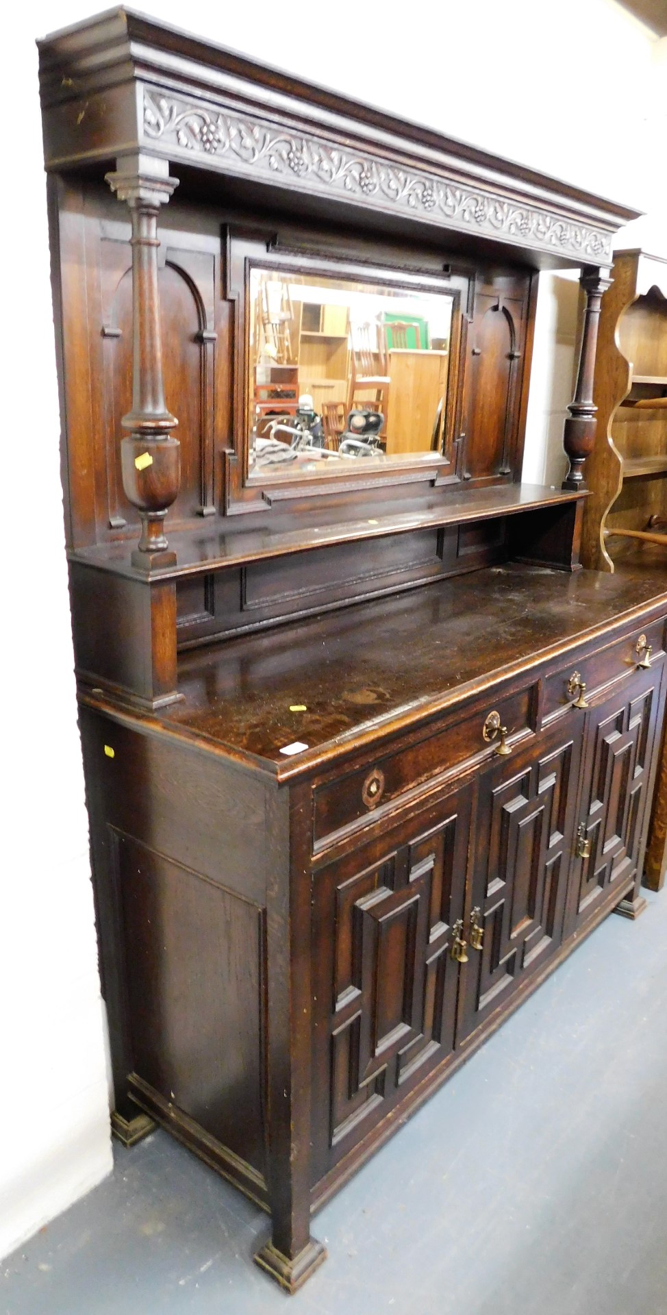 An oak dresser, the top with a moulded cornice and vine carved panel, above a mirrored back and rece