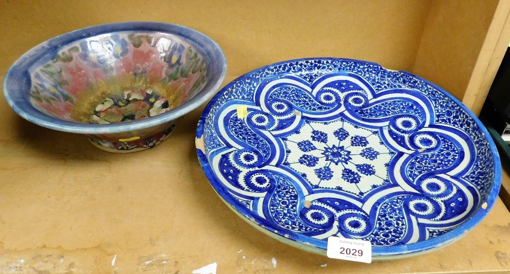 An Iznik style pottery charger, decorated in blue and white, 36cm diameter, and a studio pottery bow