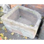 A stone corner trough, demi lune shaped, 42cm high, 76cm wide, 58cm deep.