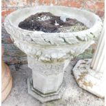 A reconstituted stone planter, the bowl with leaf moulded and applied fleur de lis decoration on an