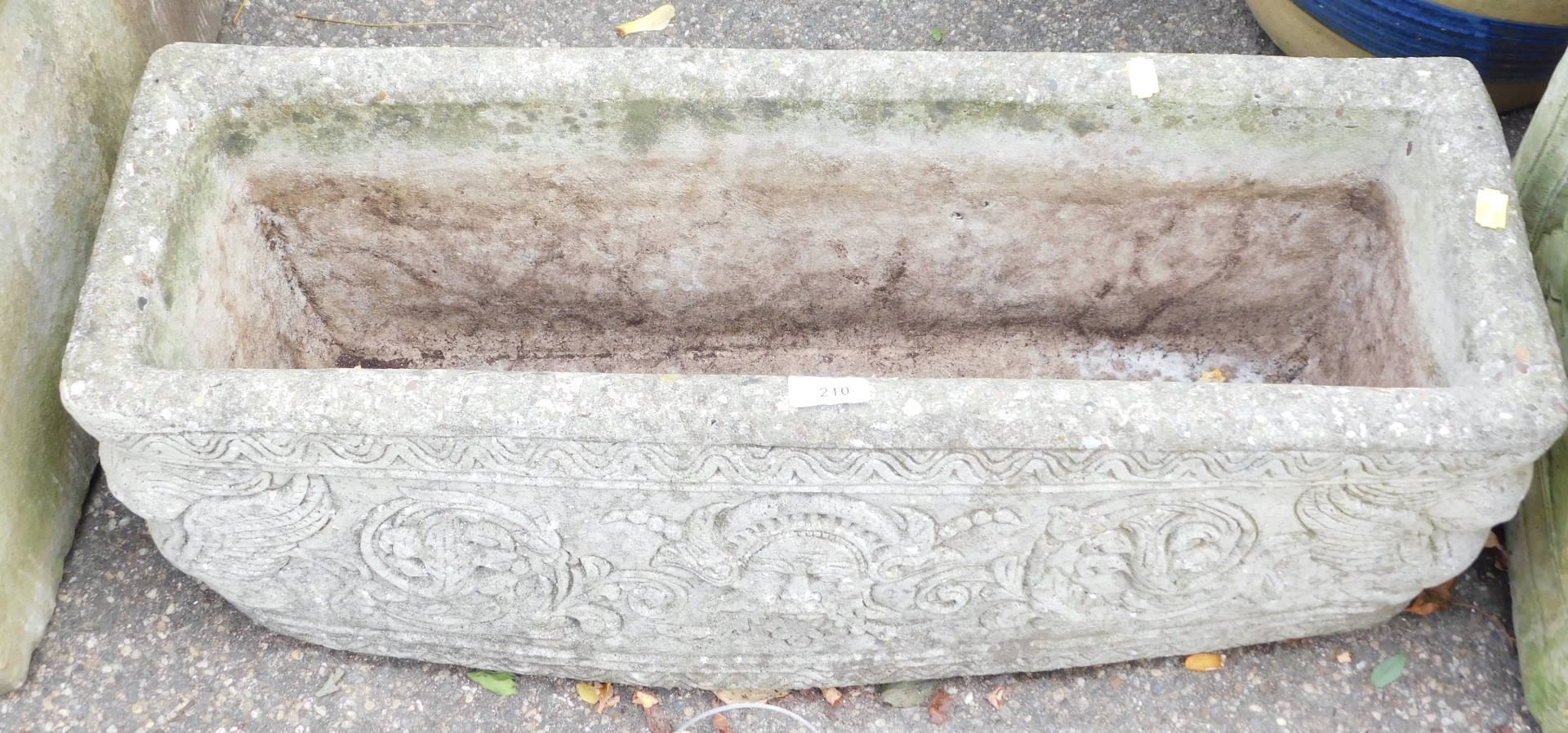 A reconstituted stone planter, rectangular with Greek god details, 25cm high, 71cm wide, 23cm deep.