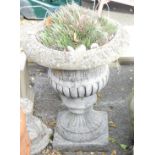 A reconstituted stone garden urn, the fluted top, on flared rim and square set base, 70cm high, 54cm