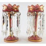 A pair of late 19thC Bohemian ruby glass lustres, with gilt highlights, floral tops, inverted stems