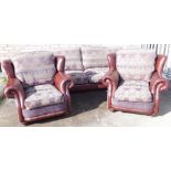 A brown leather three piece suite, with floral patterned cushions to the back and seat, on bun feet,
