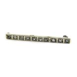 An Art Deco diamond rose cut brooch, the bar set with ten diamonds, white metal marked 18ct, diamond