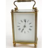 A French brass carriage clock, in shaped case with enamelled dial and swing handle, 15cm high.