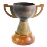 An unusual metal trophy, with angular handles, stepped circular tapering base and oak socle, the mai