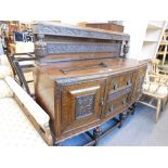 A 1920/30's oak sideboard, the raised back carved with grapes and vines, and with cup and cover supp