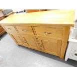 A light oak sideboard with three drawers above a triple cupboard