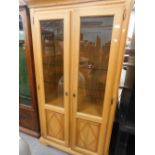 A Continental oak display cabinet, with two glazed and panelled doors enclosing glass shelves, on br