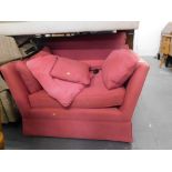 A red upholstered wide arm chair or small sofa. 122cm wide The upholstery in this lot does not compl