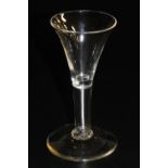 A late 18thC wine glass, possibly an Excise glass, with a trumpet shaped bowl and plain stem, raised