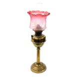 An early 20thC brass oil lamp, with a graduated pink glass shade, with etched floral decoration chim