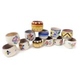 Twelve Poole pottery egg cups, traditionally painted with flowers, or with geometric banding, impres