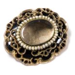 A Victorian hair locket mourning brooch, of oval form, with black enamel and yellow metal, the glass