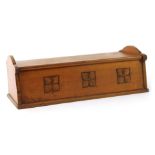 An Arts & Crafts fruitwood box, with shaped end supports, and central panel inlaid with carving of t