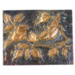 An Arts & Crafts style hammered copper panel, of two birds perched on branch with vines, on a cardbo