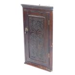 A late 19thC oak hanging corner cabinet, with single panelled door with glazed scroll and flower det