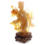 A Chinese agate figure of Guanyin, modelled standing holding a hand mirror, and a lotus flower, rais