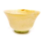 A Chinese jade tea bowl, on short foot, shading from pale green to russet, 9.5cm wide.