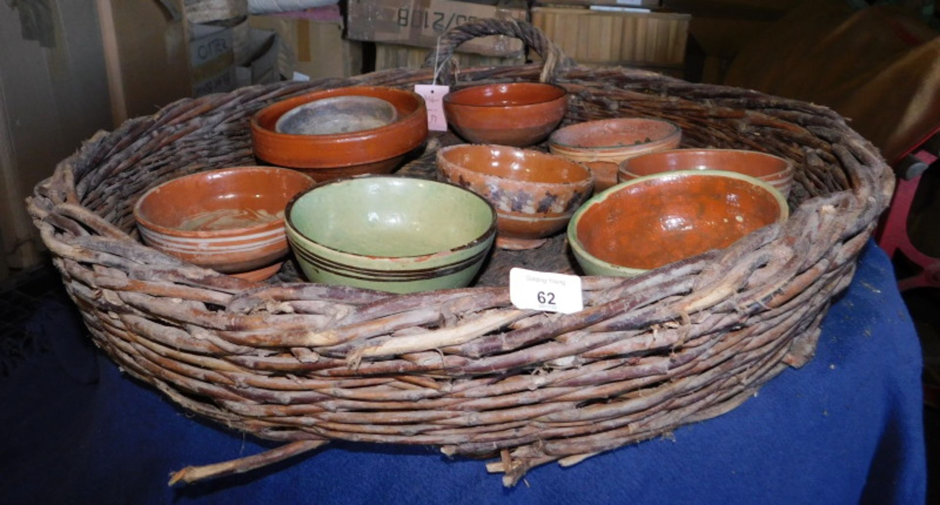 A wicker basket, of circular form with handles, containing a quantity of terracotta bowls, some pain