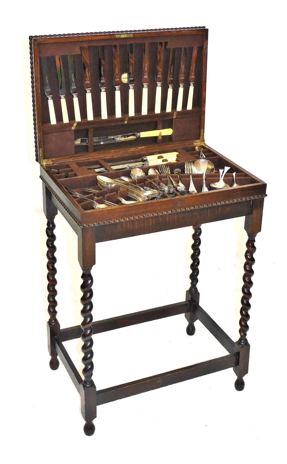 An early 20thC oak canteen table, containing mixed silver plated and stainless steel flatware, raise