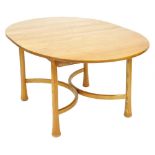 An Ercol elm draw leaf dining table, the oval top raised on turned outswept legs, united by an x fra