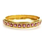 A ruby and diamond set hinged bangle, the front set with sixteen heart shaped facet cut rubies, inse