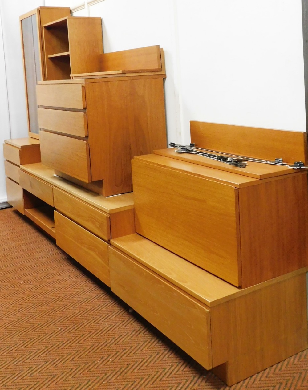 A vintage 1960's teak modular lounge unit, comprising a glazed cabinet on a three drawer chest base,