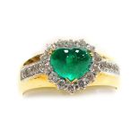 An emerald and diamond set dress ring, a central heart shaped cabachon emerald, 7mm x 5.5mm, surroun