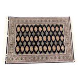 A Bokhara black ground rug, decorated with three rows of ten guls, within repeating geometric border