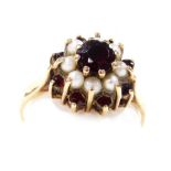 A 9ct gold garnet and seed pearl ring, of concentric flower head form, high claw set, size O, 3.0g.