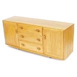 An Ercol light elm sideboard, with three central drawers flanked by cupboard doors, raised on castor