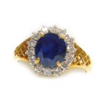 A sapphire and diamond cluster dress ring, the central stone of 6.6mm diameter surrounded by fourtee