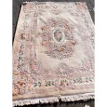 A Chinese beige ground rug, decorated with a central oval medallion of roses and laurel wreath, with