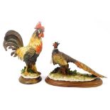 Two Capodimonte figures, one of a cockerel, raised on a wooden base, the other of a pheasant raised