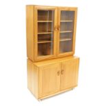 An Ercol elm kitchen dresser, with a pair of glazed doors enclosing a three shelf plate rack, above