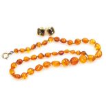 An amber bead necklace, on a bolt ring clasp, 11.6g, together with a pair of Christian Dior costume