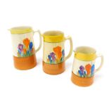 Three Clarice Cliff Bizarre graduated Autumn Crocus water jugs, printed marks, largest jug 16cm hig