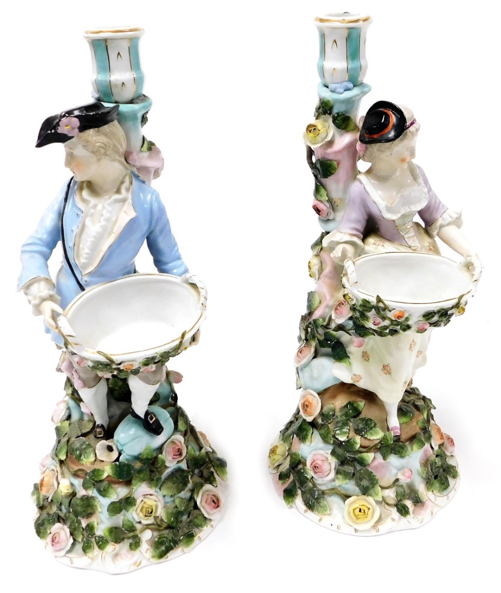 A pair of late 19thC Sitzendorf porcelain figural candlesticks, modelled as a gallant and lady, hold