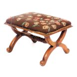 A Victorian walnut X frame stool, with a floral wool work overstuffed seat, united by a turned stret