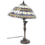 A Tiffany style table lamp, with a geometric panelled and jewel shade, raised on a stem fronted by a