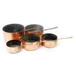 A graduated set of five copper vintage saucepans.