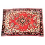 A Hamadan red ground rug, decorated with a central floral medallion, within a field of further flowe