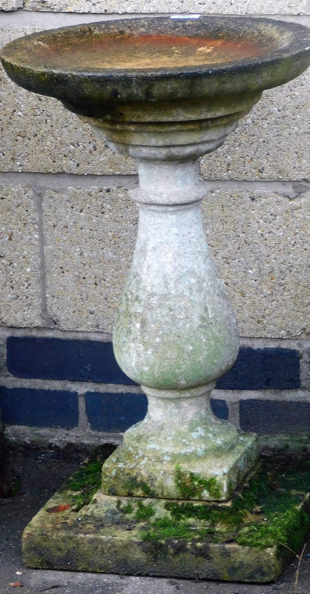 A composition bird bath, with circular top on a baluster shaped column, above a square base, 67cm hi