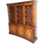 A reproduction Georgian mahogany concave library bookcase, the outswept pediment with dentil mouldin