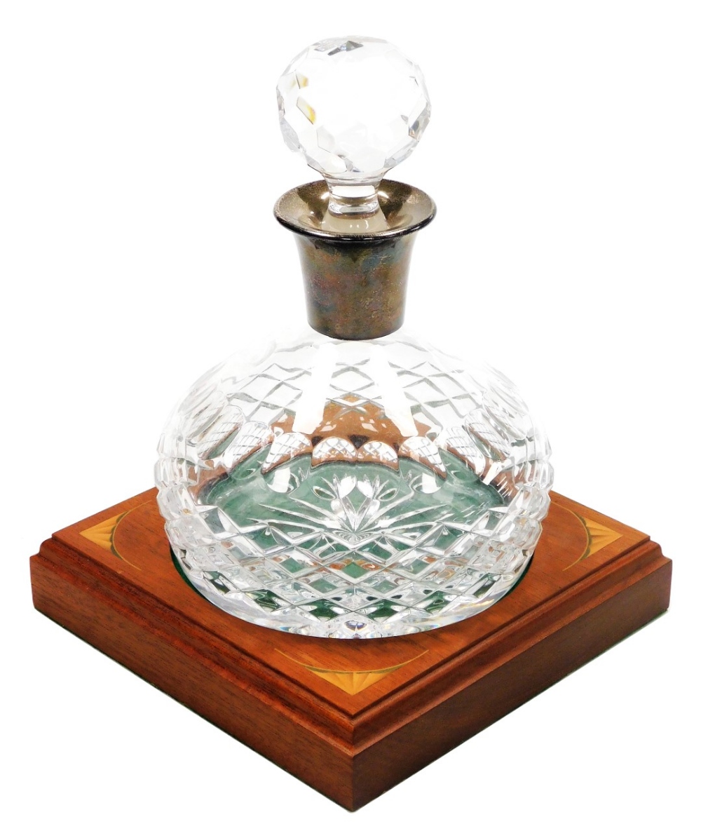 A cut glass decanter and stopper, with a silver collar, Birmingham 1987, and a mahogany stand with q