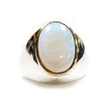 An opal set dress ring, the flat cabachon opal of 13.6mm x 9.7mm showing flashes of green, blue and